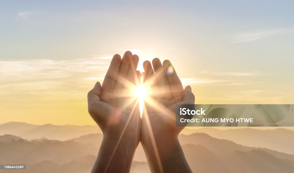 Human hands praying to god on mountain sunset background Gratitude Stock Photo
