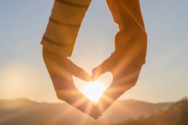 istock Silhouette hands in heart shape on mountain outdoors in summer park at sunset 1386643333