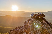 istock binoculars on top of rock mountain at beautiful sunset background. 1386643491