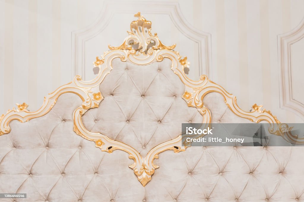Luxury royal headboard of expensive bed with golden elements and light beige textile - elegant part of bedroom interior Royalty Stock Photo