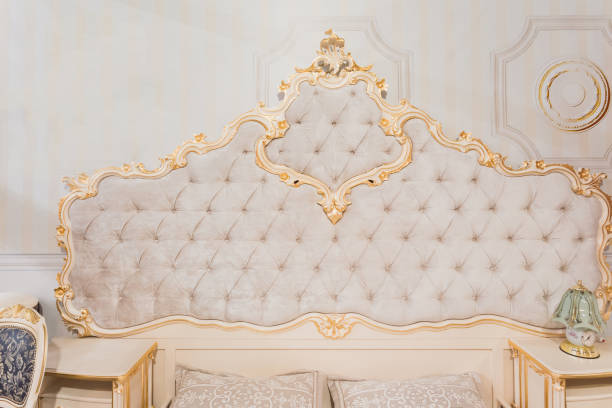 istock Luxury royal headboard of expensive bed with golden elements and light beige textile - elegant part of bedroom interior 1386646557