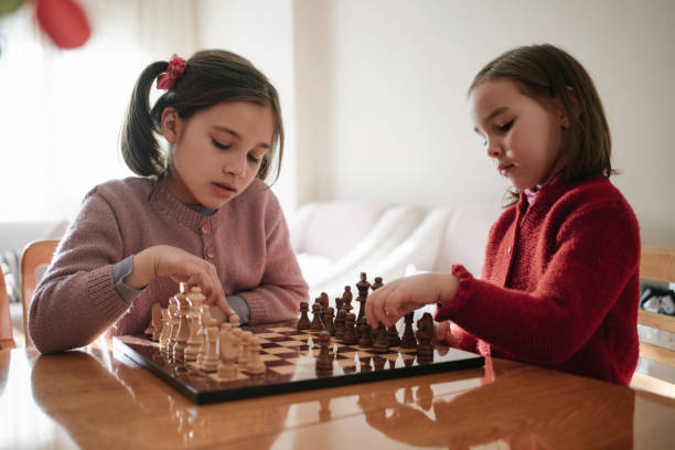 due bambine che giocano insieme a scacchi - concentration chess playing playful foto e immagini stock