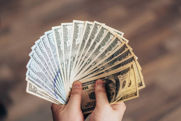 istock Hands holding one hundred dollar bills fanned out 1386663566