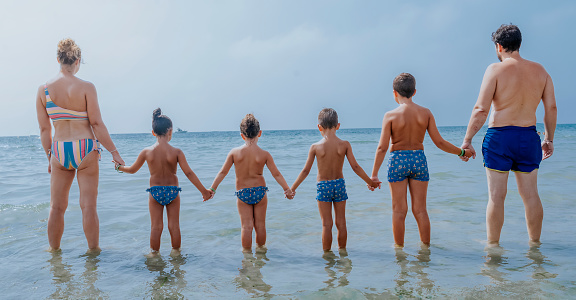 A family holding hands on the shore of the beach.