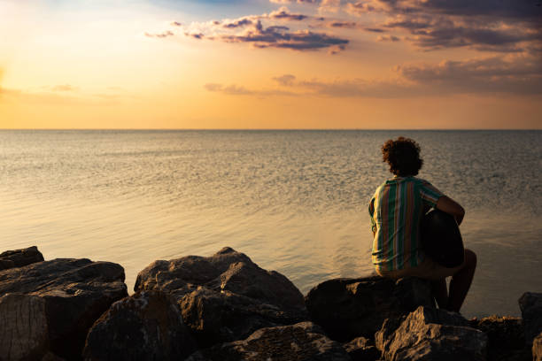 istock Back view of relaxed young man with sunset background 1386671110