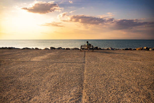 Man sitting on bench with guitar and watching beautiful sunset view.