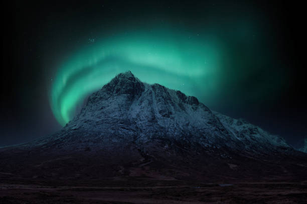 Majestic vibrant Northern Lights Aurora composite image over landscape of snowcapped mountain in Scottish Highlands stock photo