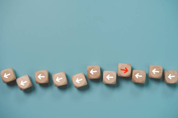 istock Disruption and technology transformation concept , Red arrow on wooden block cube move  in opposite direction from red arrow on blue background. 1386682065