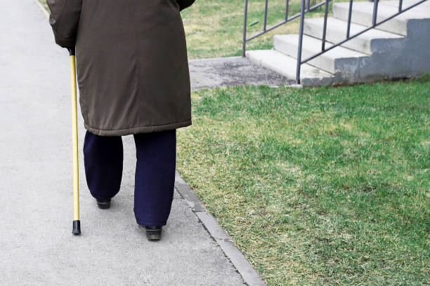 istock Pensioner old elderly man walking down the street with a cane stick 1386688502