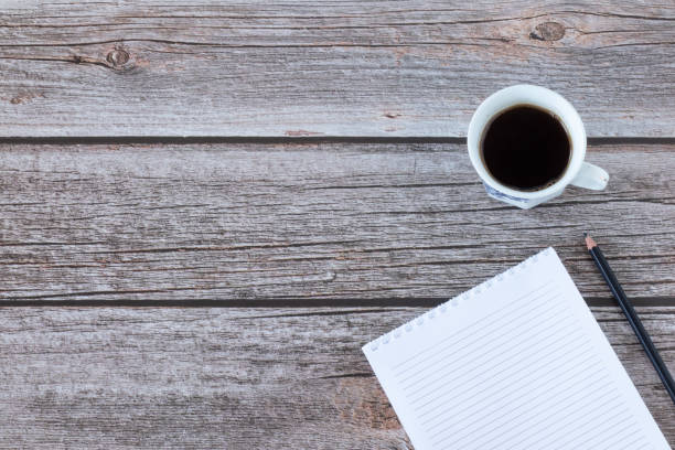 istock Blank spiral notebook with pencil, and a cup of coffee on a rustic wooden table background with copy space 1386690153