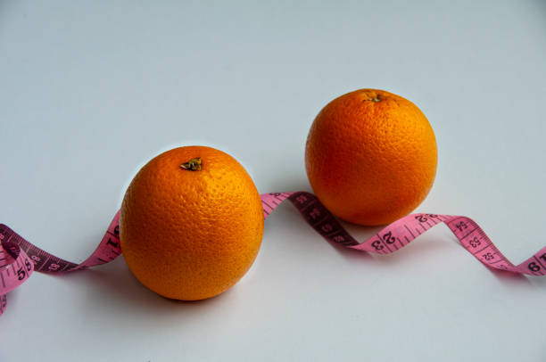 Orange with measuring tape. White background. Fitness concept
