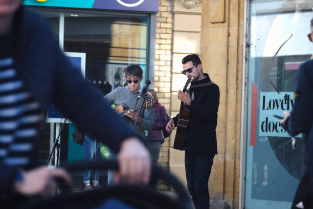 Two talented buskers play their classical guitars to passing shoppers in the town centre of the Cotswold town of Cheltenham, England