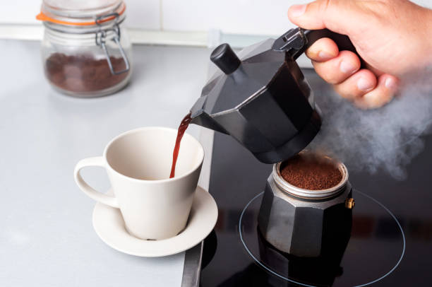 istock Disassembled coffee maker with one part on the fire and the other serving coffee in a cup. 1386693352