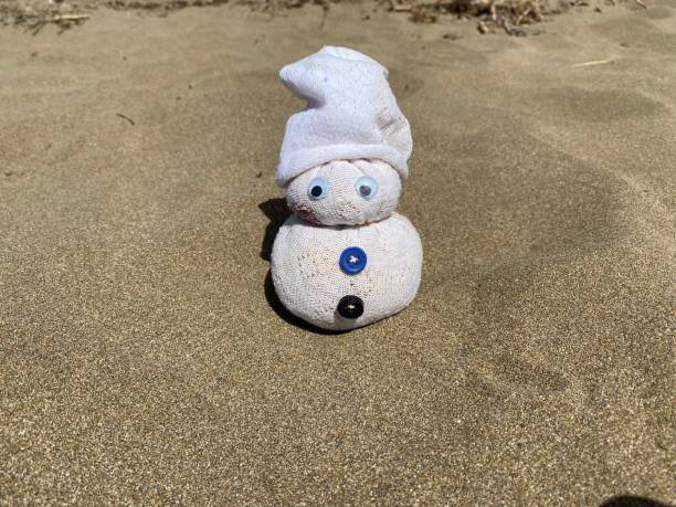 istock Cute little handmade snowman sitting on the sand 1386694738