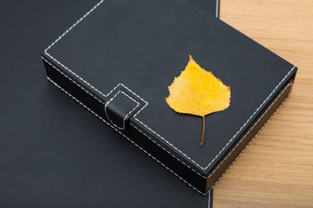 Black box for paper, document storage and a yellow leaf of a tree, on the desktop. Decor in the interior