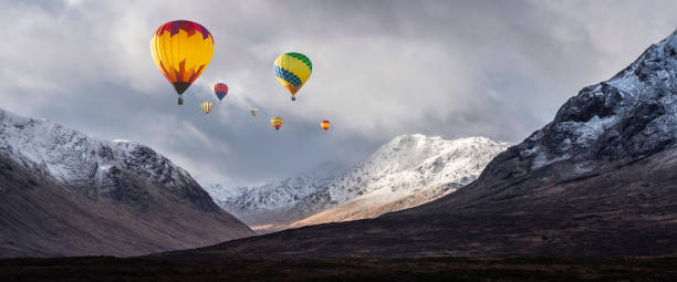 Digital composite image of hot air balloons flying over Majestic beautiful Winter landscape image of Lost Valley in Scotland Digital composite image of hot air balloons flying over Stunning beautiful Winter landscape image of Lost Valley in Scotland glen etive photos stock pictures, royalty-free photos & images