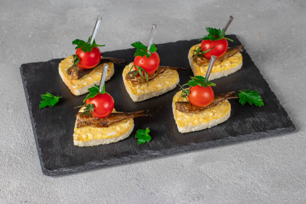 밝은 회색 배경에 슬레이트 접시에 스프래트, 치즈, 계란과 체리 토마토와 마음의 형태로 카나페, 발렌타인 데이에 대한 아이디어 - cherry valentine 뉴스 사진 이미지