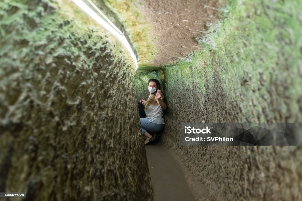 The tourist explores the underground city in Cappadocia. Turkey. The tourist explores the underground city in Cappadocia. Turkey. The young woman wanders through the tunnels of an ancient settlement. Derinkuyu Stock Photo