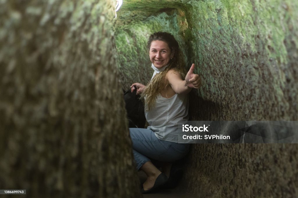 The tourist explores the underground city in Cappadocia. Turkey. The tourist explores the underground city in Cappadocia. Turkey. The young woman wanders through the tunnels of an ancient settlement. Catacomb Stock Photo