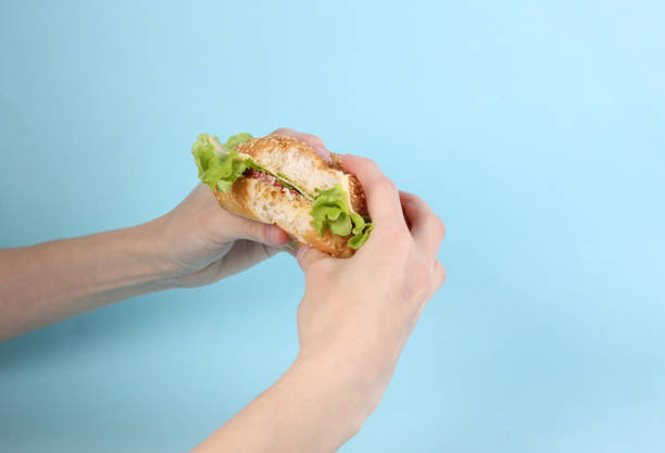 istock Hands holding a bitten homemade burger on a blue background 1386702073
