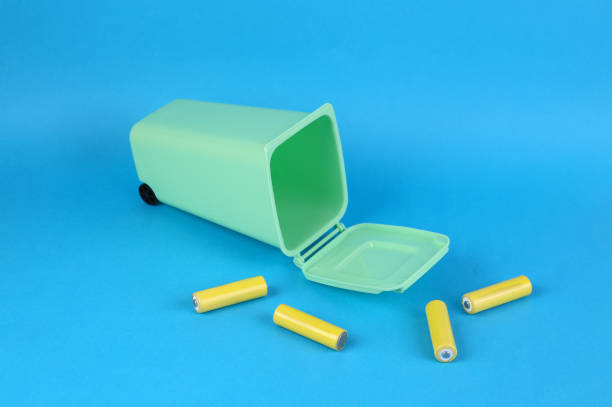 istock Battery recycling concept. Miniature trash can with aa batteries on blue background 1386702210
