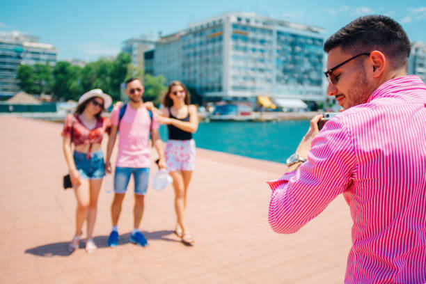 Four tourists taking a photo next to the sea while being casually dressed.