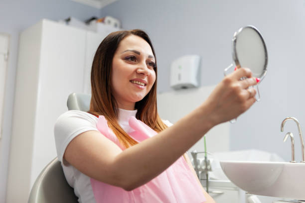 Happy woman looks at her smile in the mirror on visit to the dentist in dental office. Beautiful smile, whitening, dental treatment concept Happy woman looks at her smile in the mirror on visit to the dentist in dental office. Beautiful smile, whitening, dental treatment concept ambulant patient stock pictures, royalty-free photos & images