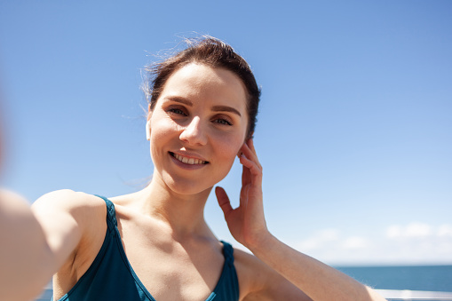 Selfie portrait of an attractive woman jogging on a bright sunny embankment