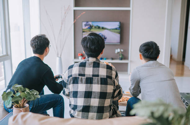 rear view asian chinese young man enjoy playing video games with his friend in living room during weekend - racing game imagens e fotografias de stock