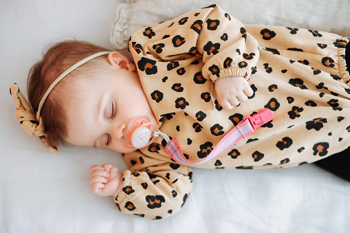 Little girl in pajamas with formula bottle getting ready to sleep in crib, lamp and toy bear. Bed time drink for kids.