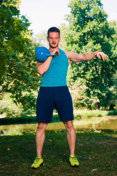 istock Man holding kettlebell while training his body in the park 1386709470