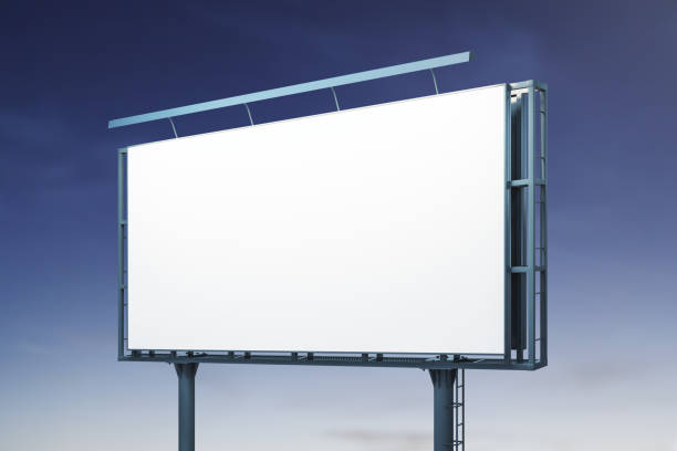 istock Blank white horizontal billboard on blue sky background at night, perspective view. Mockup, advertising concept 1386710612
