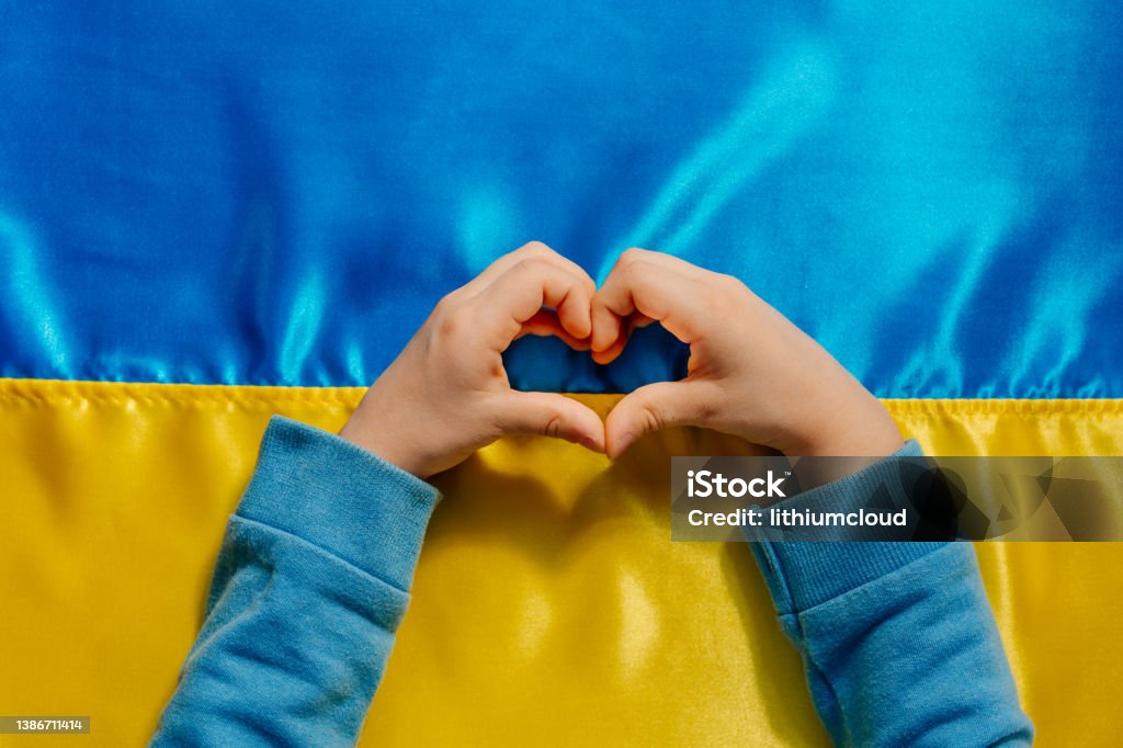 Kids hands in a heart shape on the Ukrainian flag background Kids hands in a heart shape on the Ukrainian flag background. Symbol of peace and pray for Ukraine. Top view, flat lay. Ukraine Stock Photo
