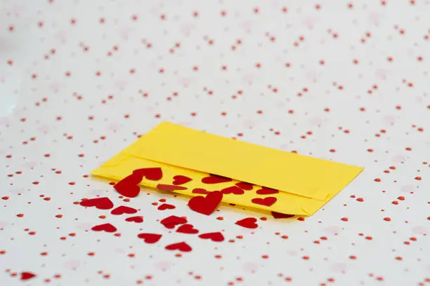 Red little hearts coming out from yellow envelope on valentine day background with copy space, loveletter concept, close-up