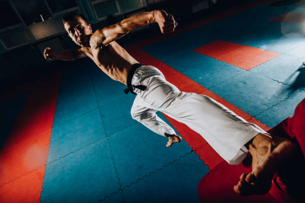 istock Boxer aggressively punching with a kick a sand bag isolated on black wall 1386712776