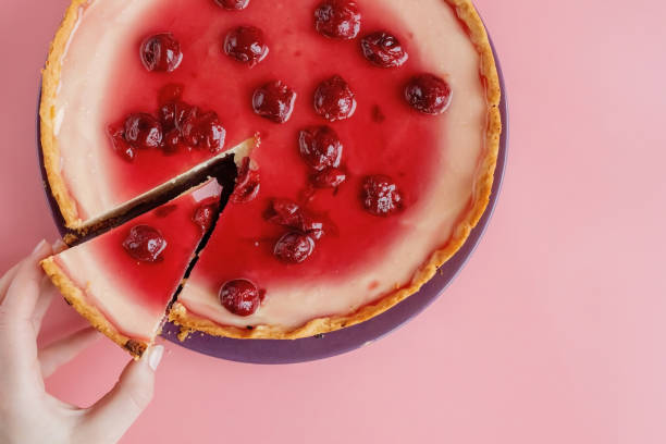 istock Slice of plain cheesecake with cranberry sauce on white plate decorated with mint leaf. Closeup view 1386713470
