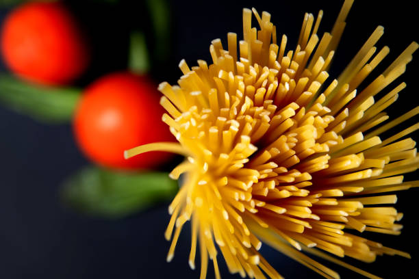 Spaghetti paste, tomato and other products for cooking on dark background top view. Space for text, top view.