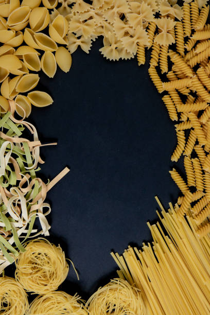 istock Assortment of different types of pasta dry on black background. 1386714120