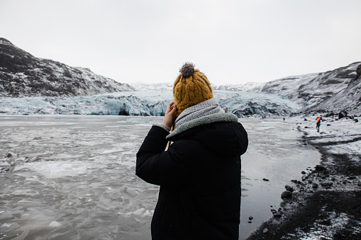 A woman take a photo of glacier on her smartphone