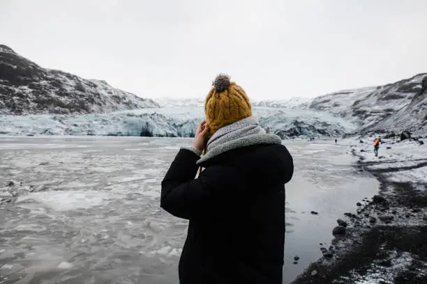 A woman take a photo of glacier on her smartphone during her journey to Iceland