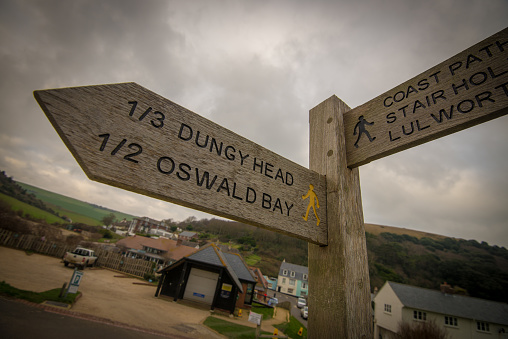 A wooden sign indicates the distance along rural walking paths.