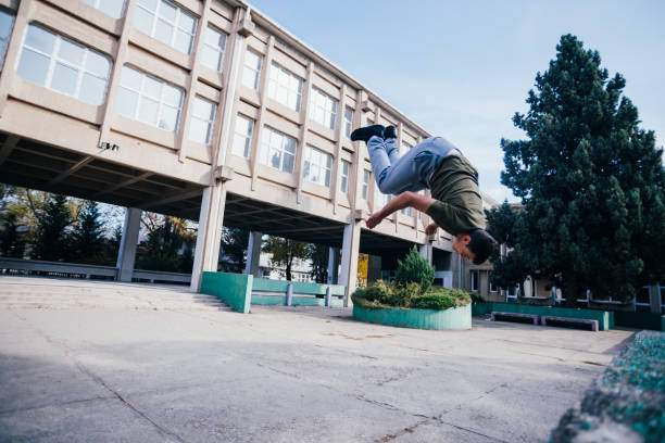 istock Athletic Parkour guy doing backflip and tricks while jumping off and over 
a concrete wall. 1386715640