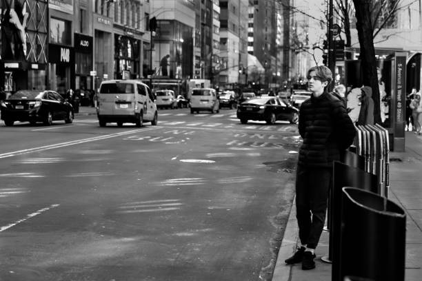 Teenage boy standing alongside Fifth Avenue in Manhattan stock photo