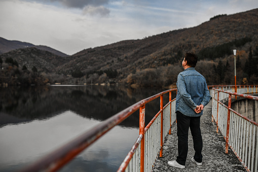 Daydreaming Senior Male Walking On River Dam And Thinking Of Improving Future Of Planet