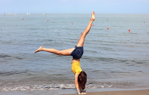 slender athletic girl barefoot on the seashore while effect the rhythmic gymnastics exercises