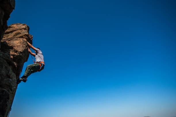 istock The man climbs the rock against the sky 1386718269