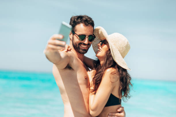 istock couple take a selfie on the beach in summer 1386720474