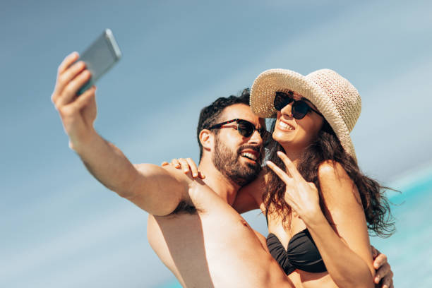 istock couple take a selfie on the beach in summer 1386720479