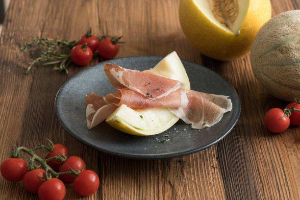 istock Sliced of Galia melon with iberico ham on a dark plate on rustic table 1386722928