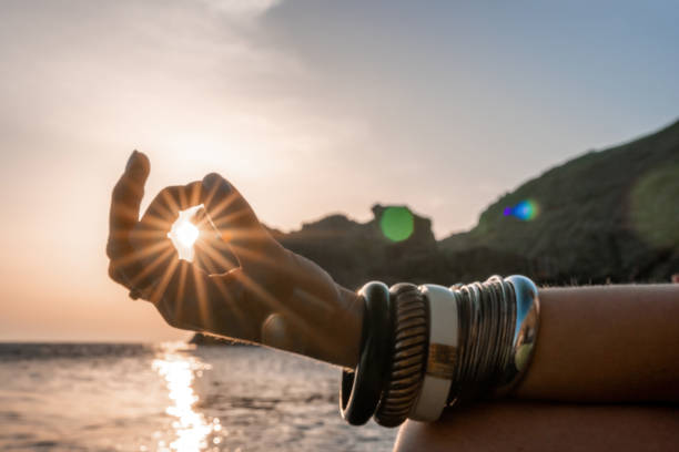 istock Young woman with long hair in white swimsuit and boho style braclets practicing outdoors on yoga mat by the sea on a sunset. Women's yoga fitness routine. Healthy lifestyle, harmony and meditation 1386725469